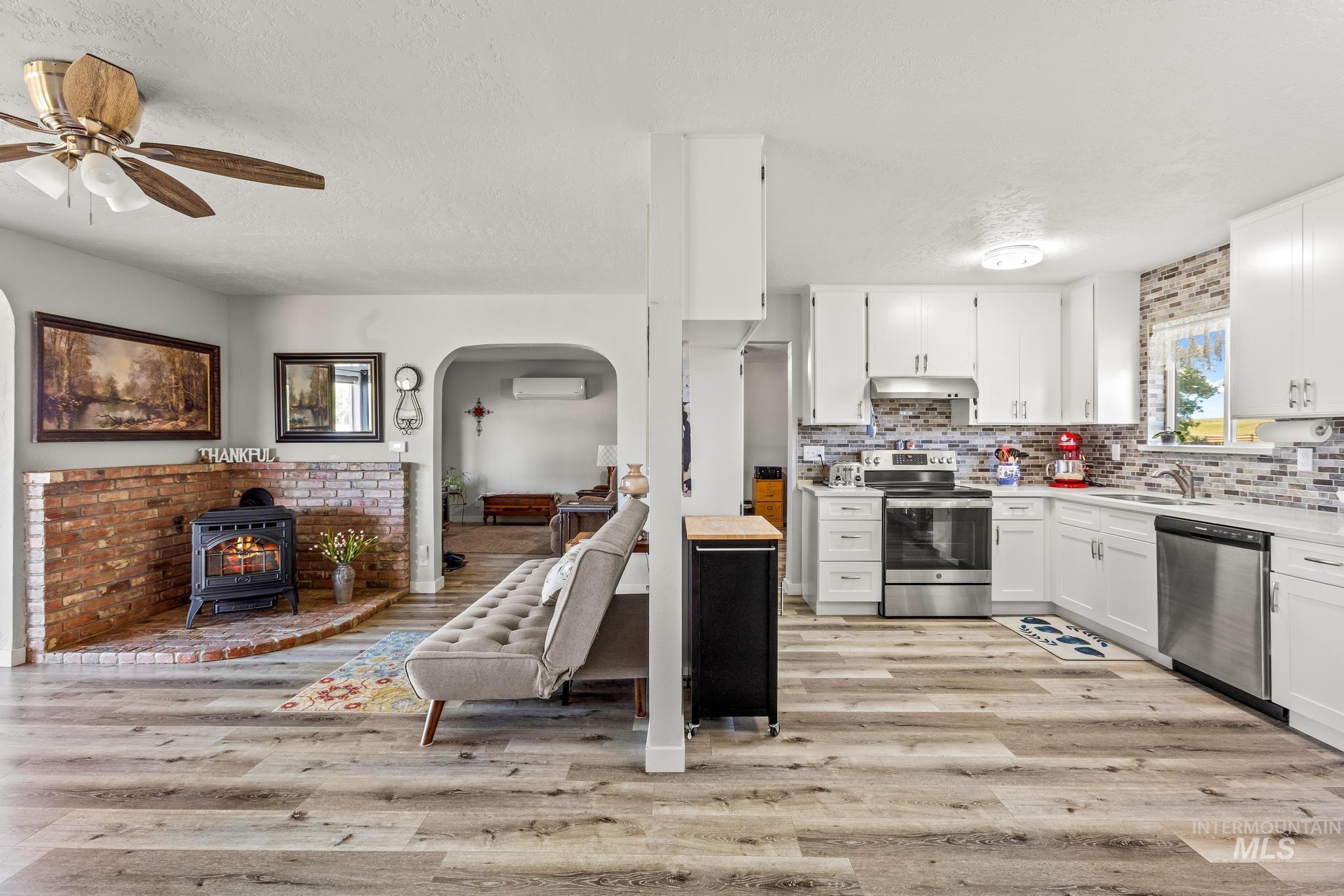 2208 Keithley Creek Road Midvale, ID 83645 - Photo 12 of 45 Kitchen with stainless steel appliances, a wood stove, a wall unit AC, light wood-type flooring, and light countertops