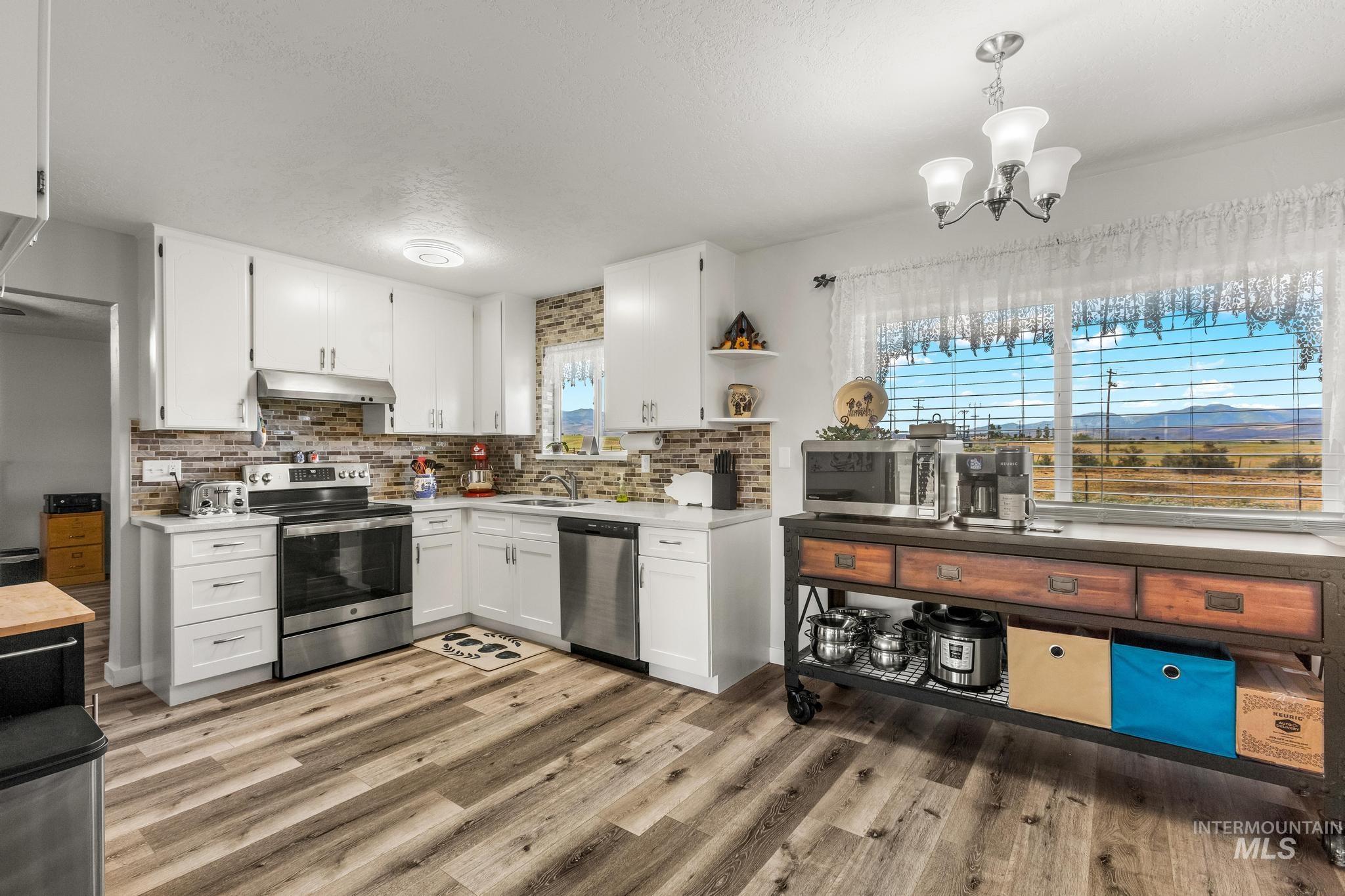 2208 Keithley Creek Road Midvale, ID 83645 - Photo 13 of 45 Kitchen featuring stainless steel appliances, under cabinet range hood, white cabinetry, decorative backsplash, and a textured ceiling