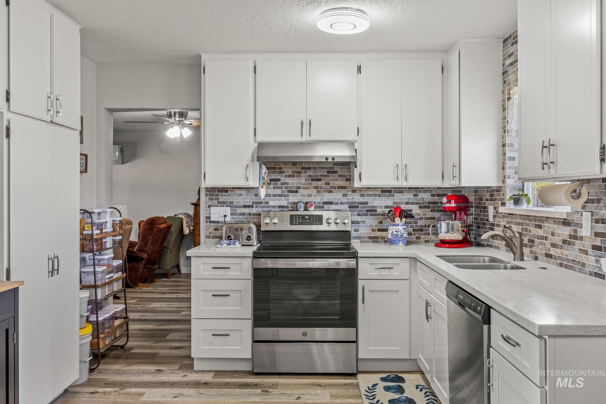 2208 Keithley Creek Road Midvale, ID 83645 - Photo 14 of 45 Kitchen with appliances with stainless steel finishes, under cabinet range hood, light countertops, light wood finished floors, and white cabinetry