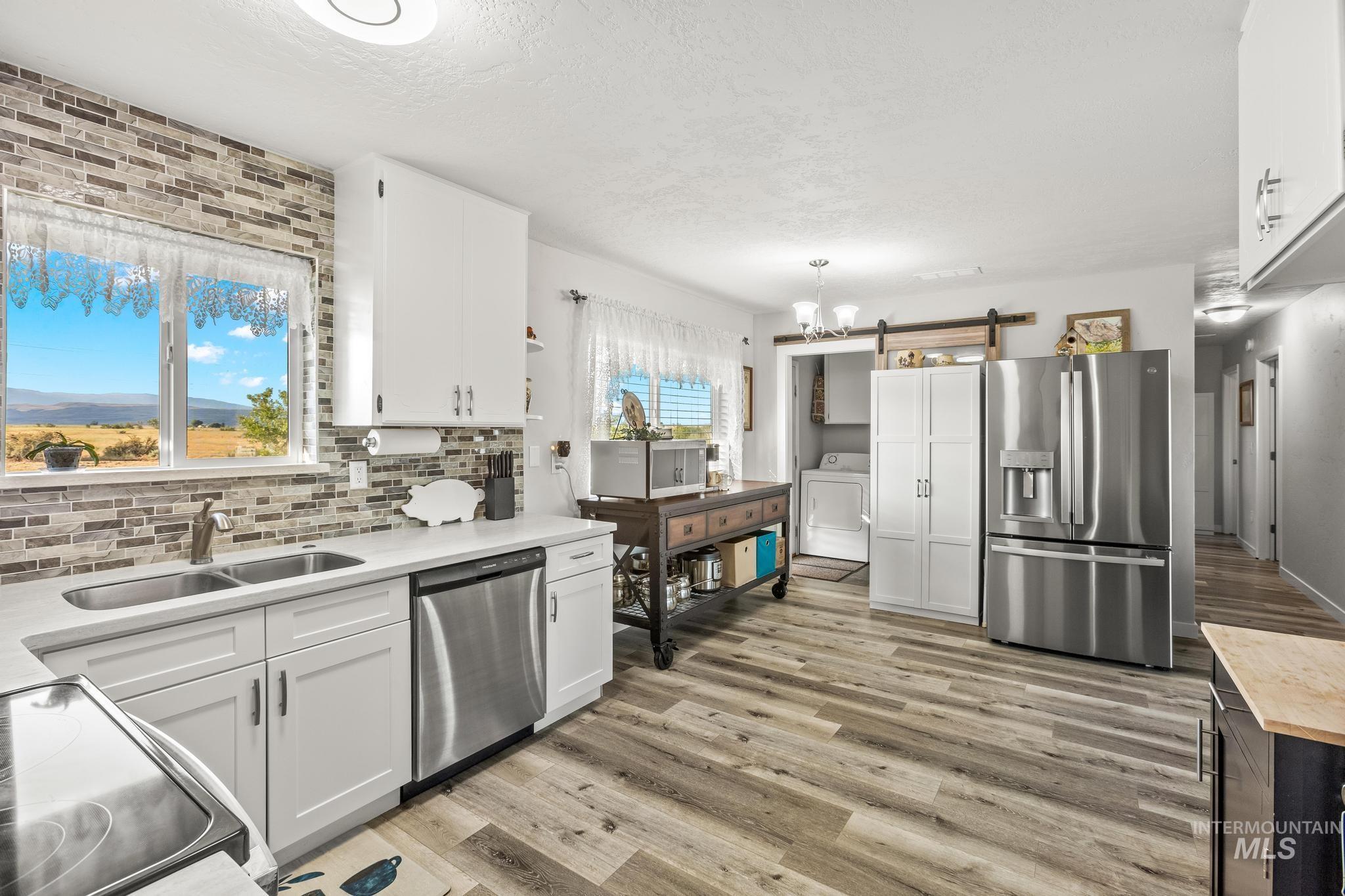 2208 Keithley Creek Road Midvale, ID 83645 - Photo 15 of 45 Kitchen with stainless steel appliances, washer / dryer, a barn door, light countertops, and white cabinets