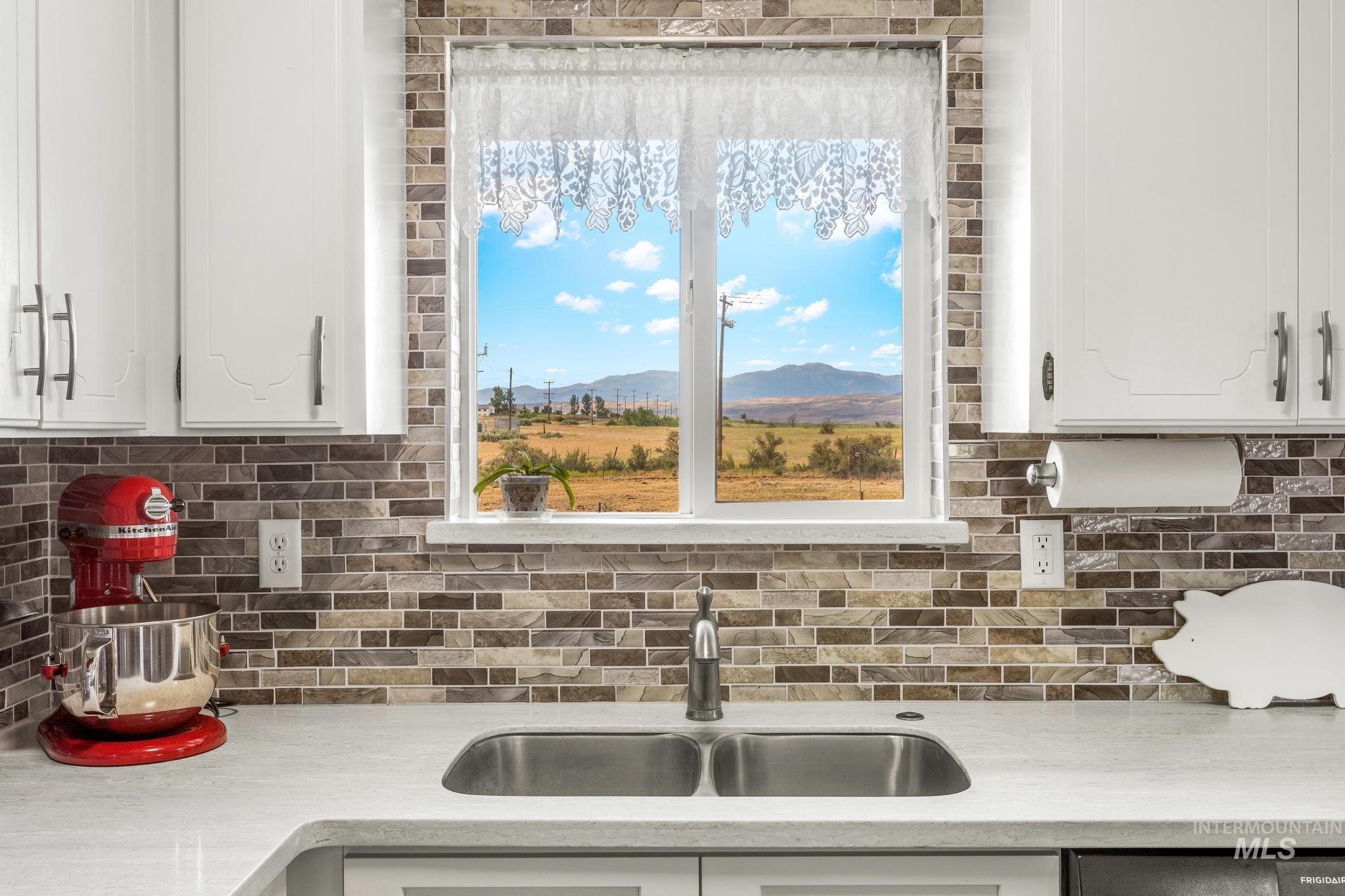 2208 Keithley Creek Road Midvale, ID 83645 - Photo 16 of 45 Kitchen featuring light countertops, backsplash, and white cabinets