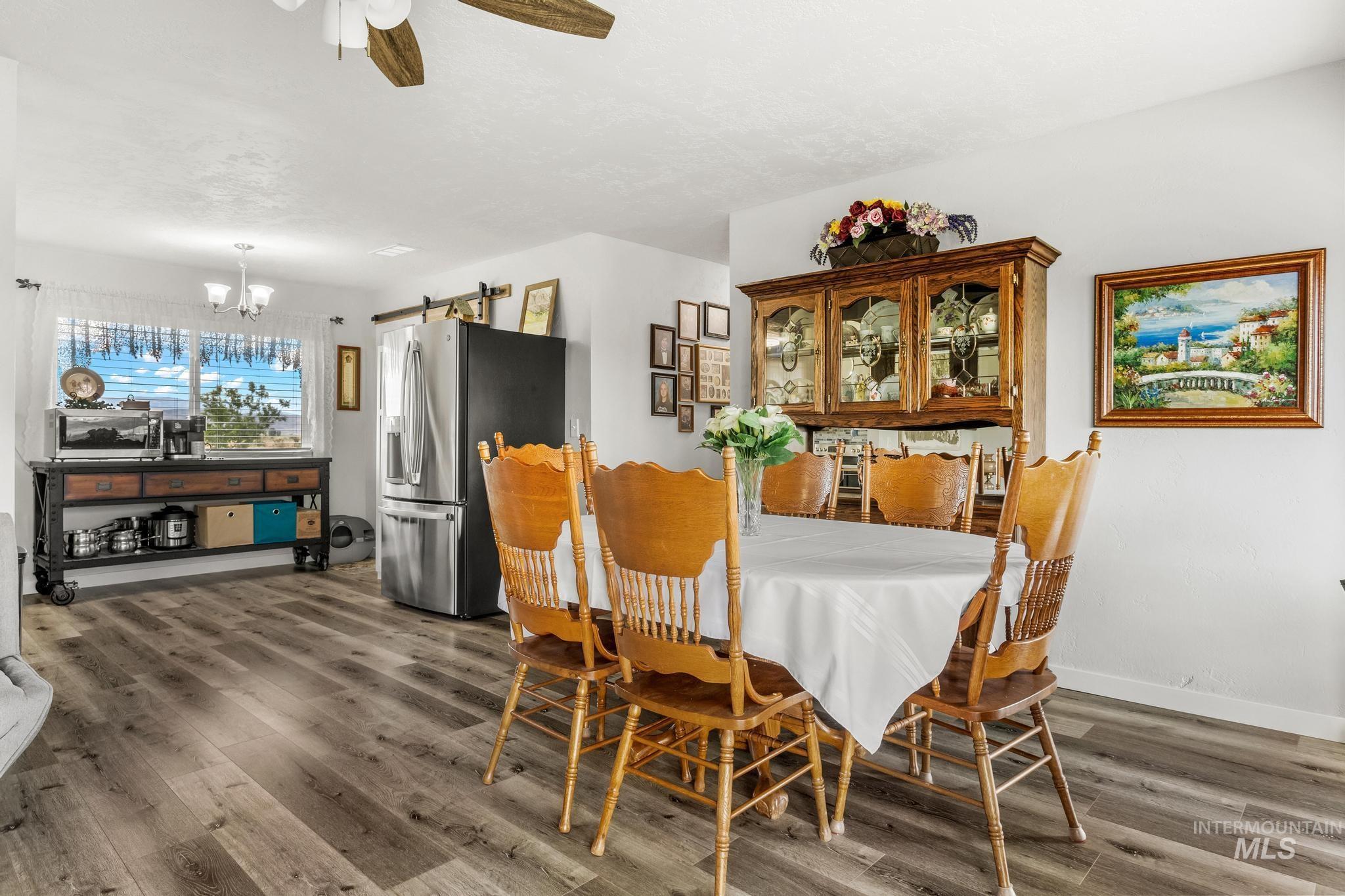2208 Keithley Creek Road Midvale, ID 83645 - Photo 18 of 45 Dining area featuring a barn door, wood finished floors, a chandelier, and ceiling fan