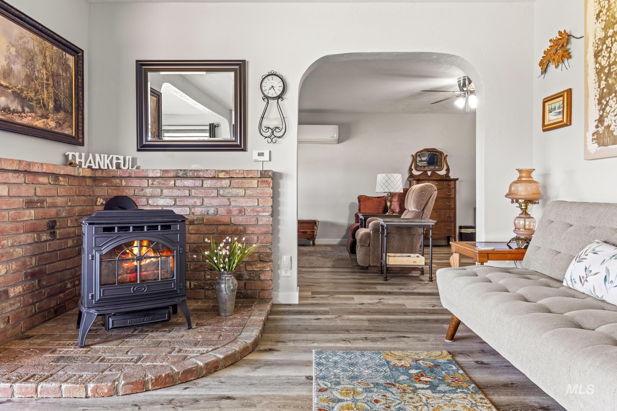 2208 Keithley Creek Road Midvale, ID 83645 - Photo 20 of 45 Living area featuring a wall mounted air conditioner, a wood stove, wood finished floors, a ceiling fan, and arched walkways