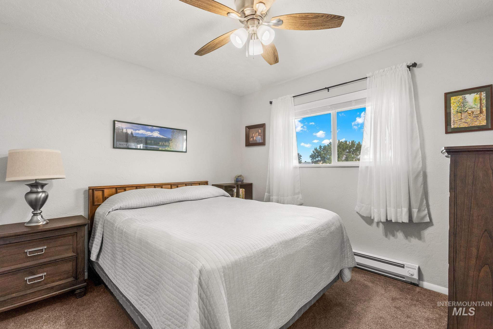 2208 Keithley Creek Road Midvale, ID 83645 - Photo 27 of 45 Bedroom featuring a baseboard heating unit, dark carpet, and a ceiling fan
