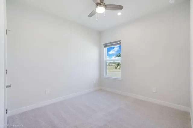 an empty room with a window and a fan