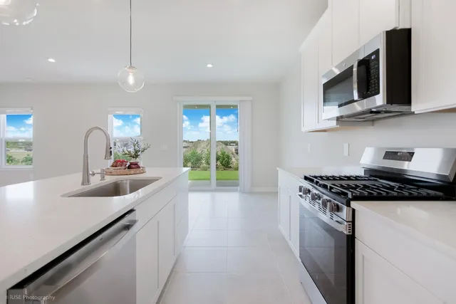 a kitchen with stainless steel appliances granite countertop a sink a stove top oven a counter space and cabinets