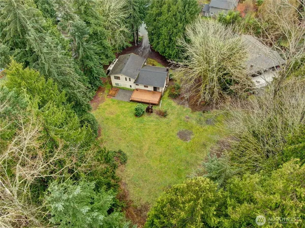 an aerial view of a house with swimming pool and large trees