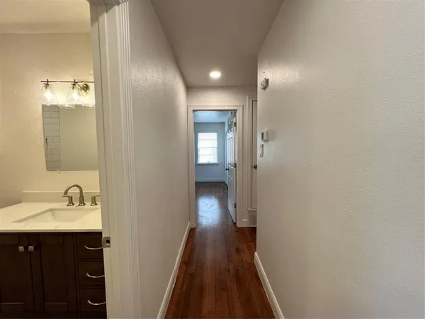 a view of a hallway with wooden floor and a bathroom