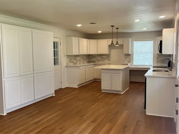 a kitchen with kitchen island white cabinets stainless steel appliances a sink and wooden floor