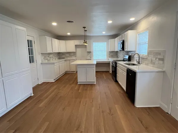 a kitchen with stainless steel appliances granite countertop a stove top oven a sink dishwasher and a refrigerator with wooden floor