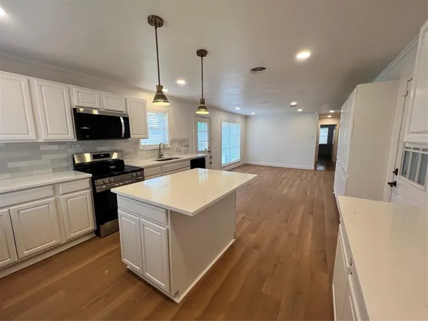 a kitchen that has a lot of cabinets and wooden floor
