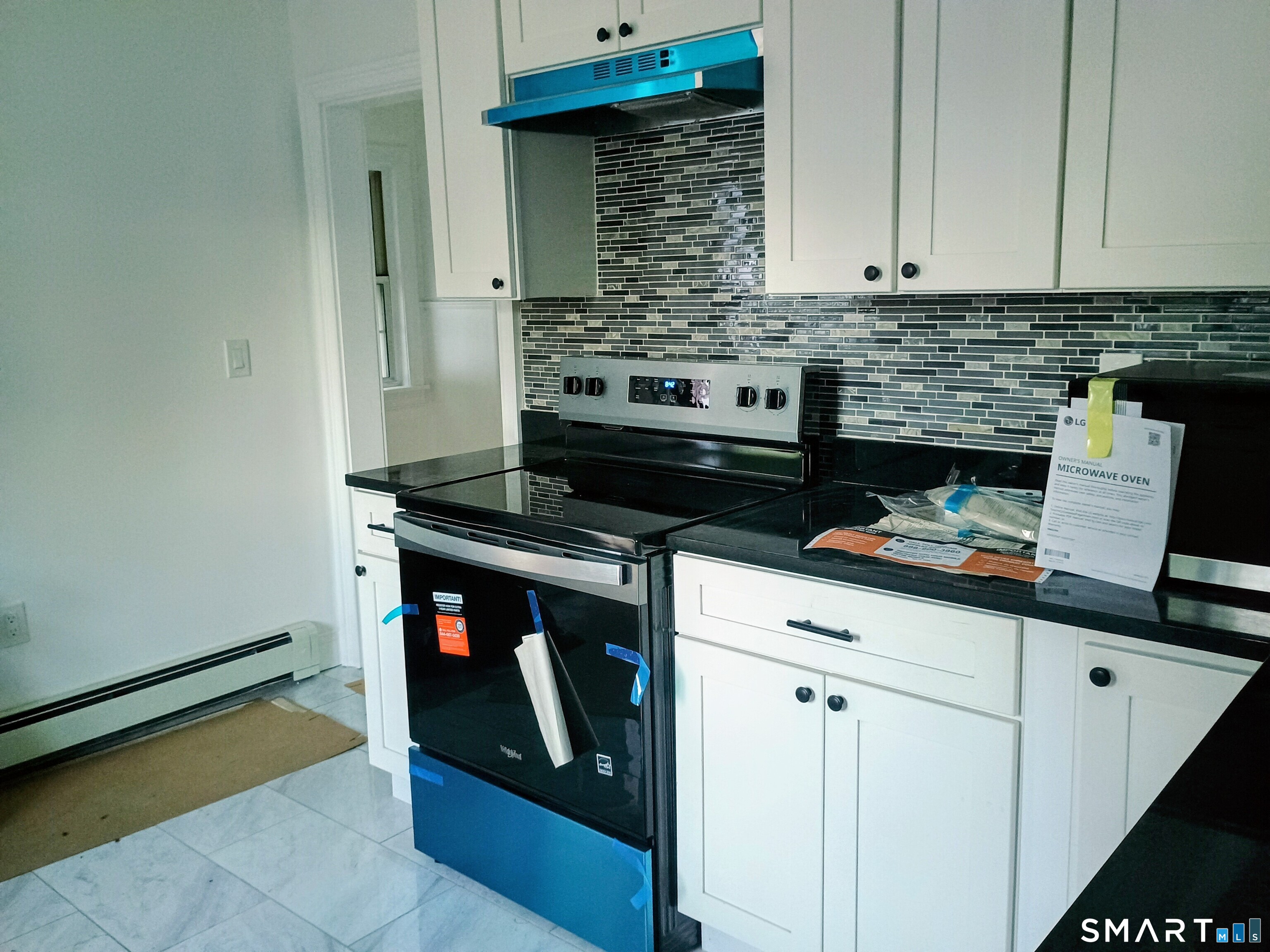 633 Wauregan Road Brooklyn, CT 06234 - Photo 3 of 17 a kitchen with a stove and white cabinets