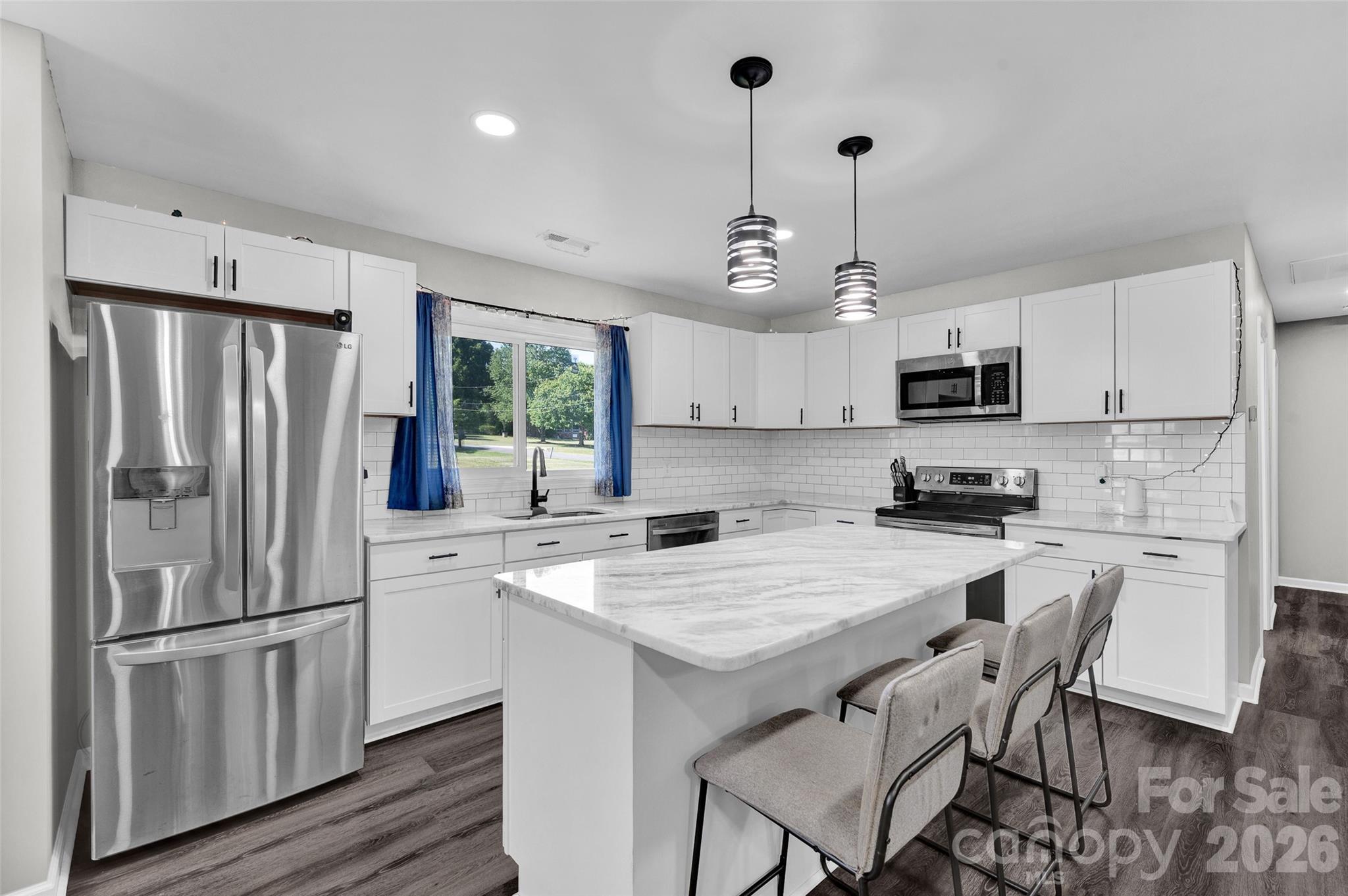 3033 West Highway 10 Conover, NC 28613 - Photo 13 of 26 a kitchen with stainless steel appliances granite countertop a refrigerator a stove a sink dishwasher a dining table and chairs with wooden floor