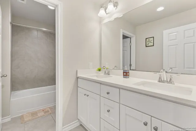 a bathroom with a double vanity sink a mirror and a bathtub