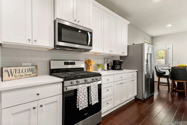 a kitchen with stainless steel appliances granite countertop a stove a refrigerator a sink a stove and white cabinets