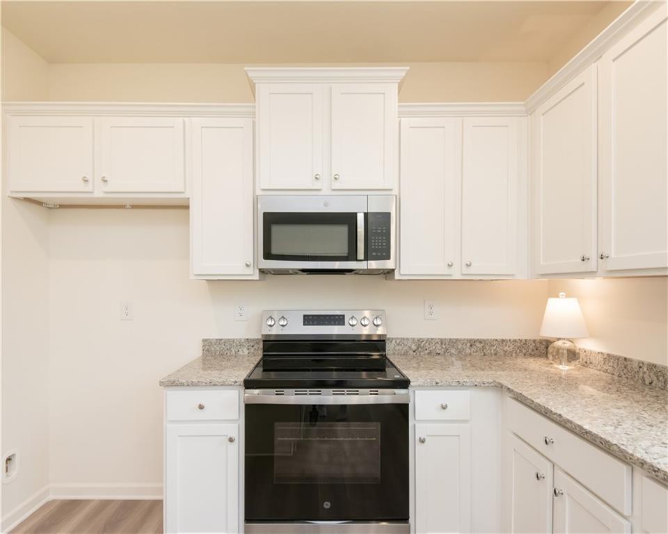 1819 Dawn Road, Unit 16 Conyers, GA 30013 - Photo 11 of 28 a kitchen with granite countertop white cabinets and stainless steel appliances