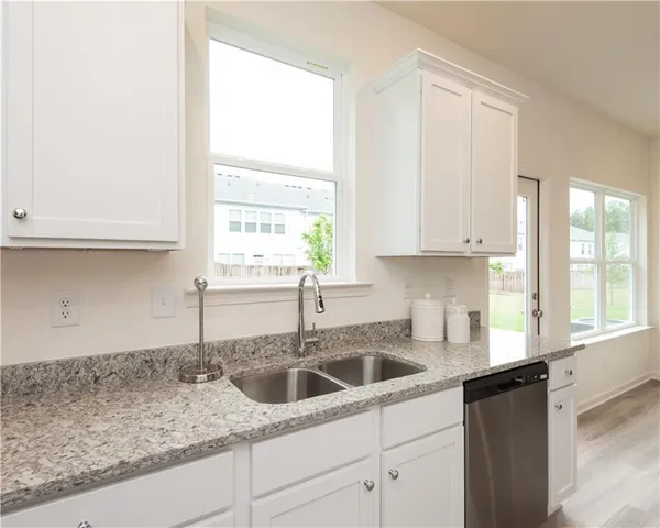 a kitchen with granite countertop white cabinets and a window