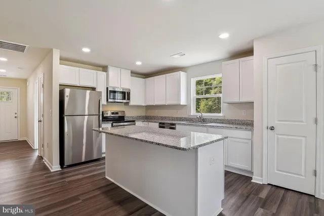 a hall with kitchen island granite countertop wooden floor and a large window