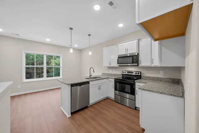 a kitchen with stainless steel appliances granite countertop a stove a sink and a microwave