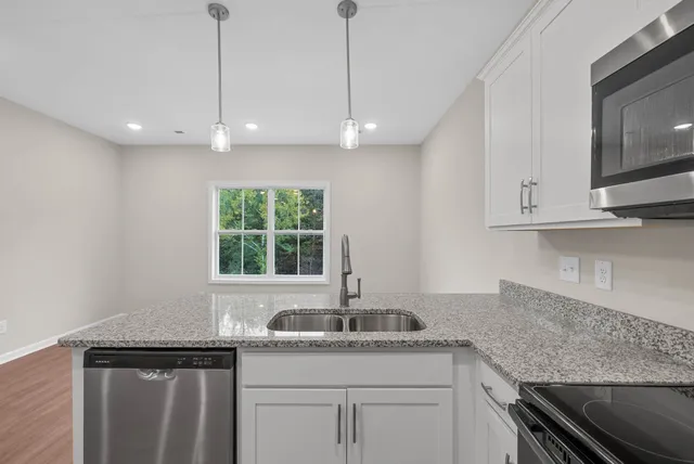 a kitchen with stainless steel appliances granite countertop a sink a window and cabinets