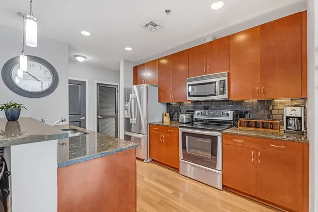 a large kitchen with stainless steel appliances granite countertop a stove a sink and a refrigerator