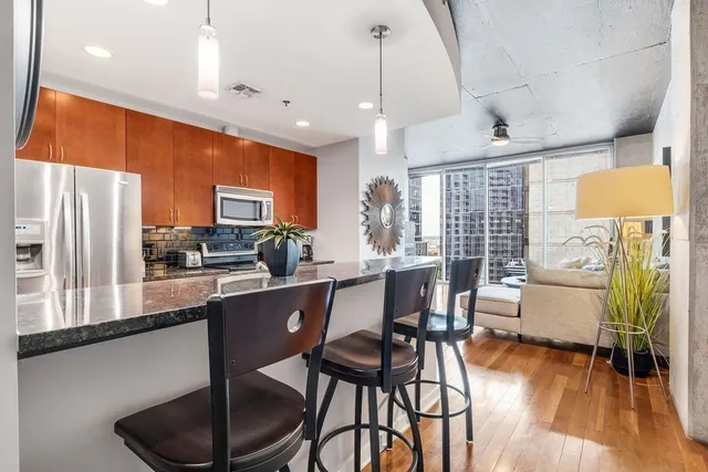 a kitchen with stainless steel appliances kitchen island granite countertop a table chairs and a refrigerator