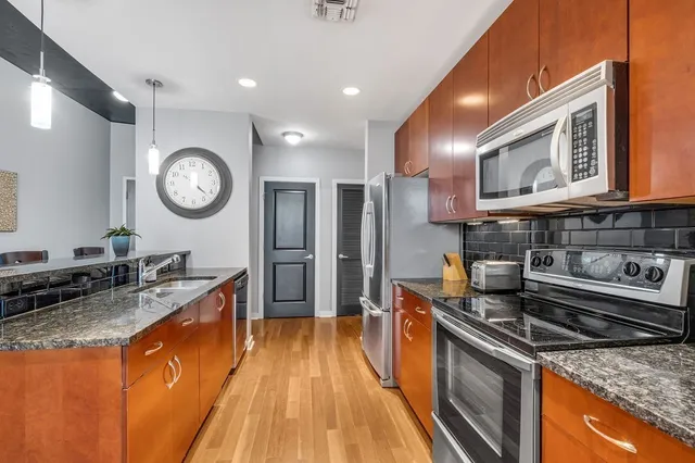 a kitchen with stainless steel appliances granite countertop a refrigerator a stove and a sink