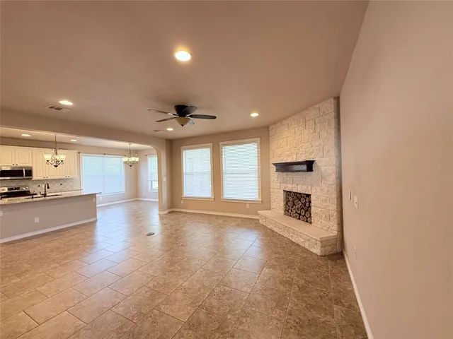 a view of an empty room and a kitchen with a sink
