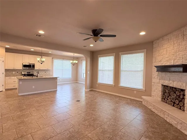 a view of an empty room with kitchen and window