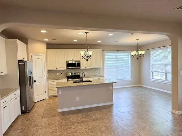 a kitchen with kitchen island a counter top space a sink stainless steel appliances and cabinets