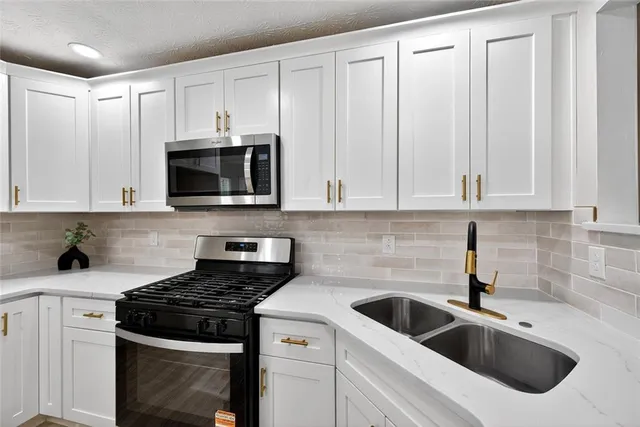 a kitchen with white cabinets and appliances