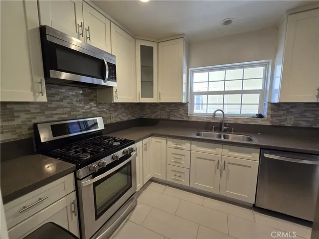 a kitchen with granite countertop white cabinets stainless steel appliances and a sink