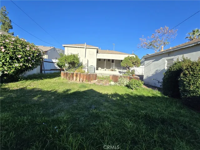 a view of a house with a big yard potted plants and large tree
