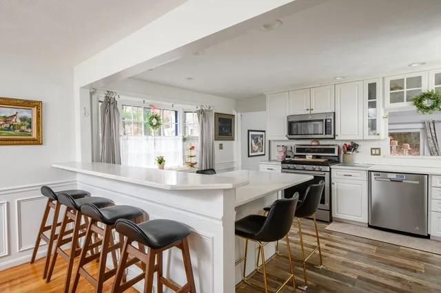 a kitchen with stainless steel appliances kitchen island granite countertop a table chairs microwave and sink