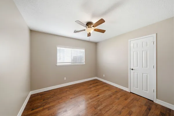 a view of a room with wooden floor and a ceiling fan