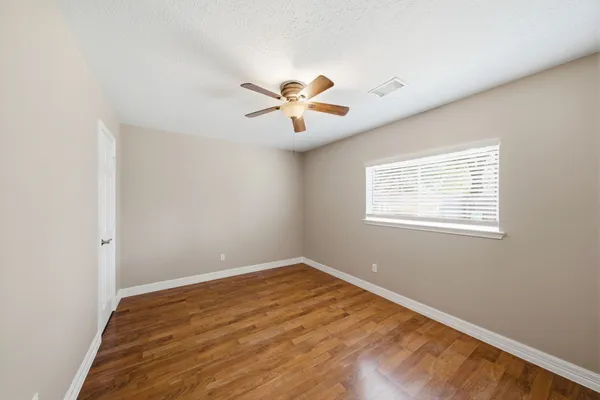 an empty room with a window and a fan