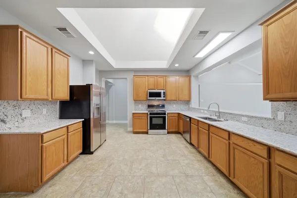 a large kitchen with stainless steel appliances kitchen island granite countertop a sink and cabinets