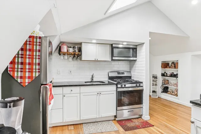 a kitchen with stainless steel appliances granite countertop a stove a sink and a microwave