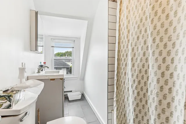 a bathroom with a sink a toilet a mirror and shower curtain