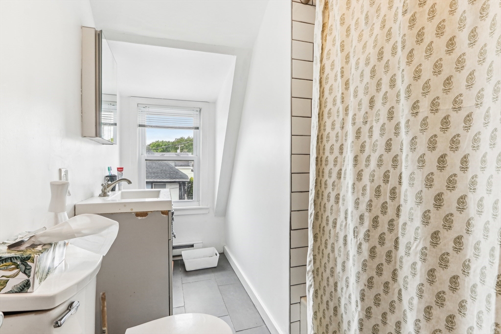 831 North Shore Road Revere, MA 02151 - Photo 19 of 24 a bathroom with a sink a toilet a mirror and shower curtain