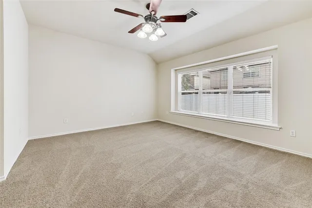 an empty room with chandelier fan and windows