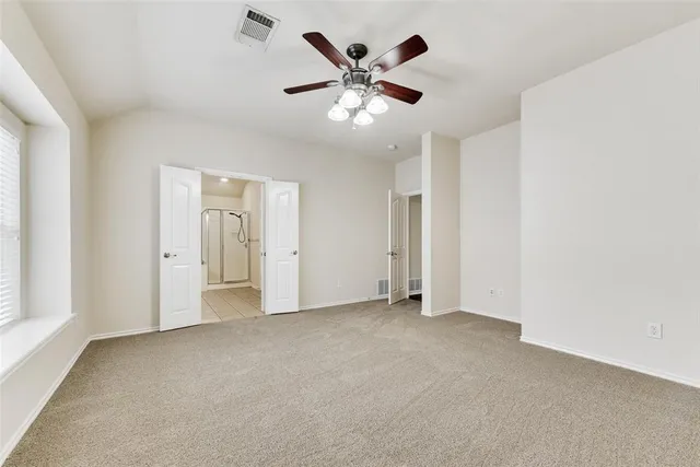 an empty room with ceiling fan and window