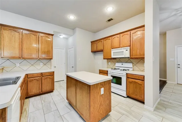 a kitchen with stainless steel appliances granite countertop a stove top oven a sink dishwasher and a refrigerator