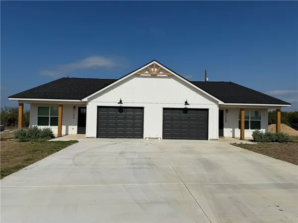 a front view of a house with yard and parking