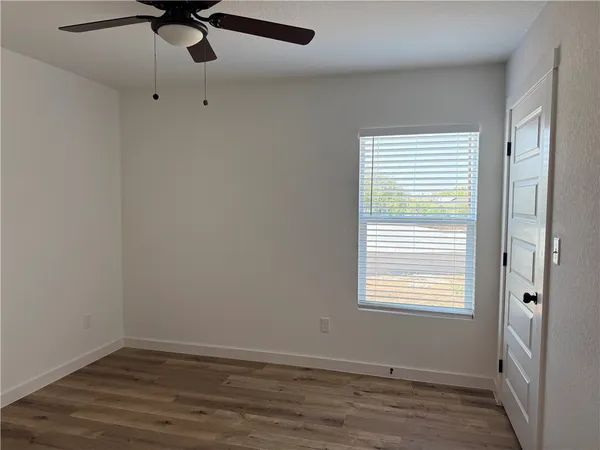 a view of an empty room with a window and wooden floor