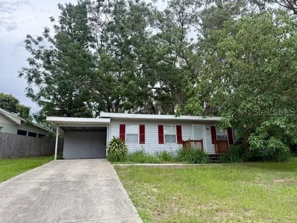 a view of a house with a yard and large tree