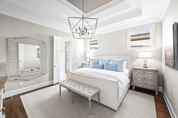 a spacious bedroom with a bed a chandelier and a dresser