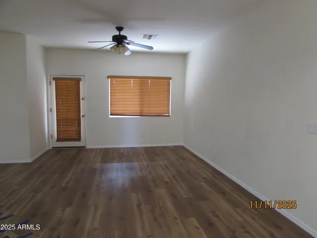 an empty room with wooden floor chandelier fan and windows