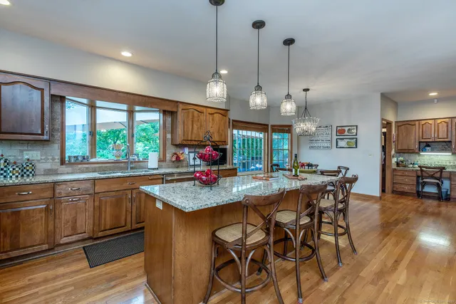 a kitchen with stainless steel appliances granite countertop wooden cabinets a stove a sink and a large window