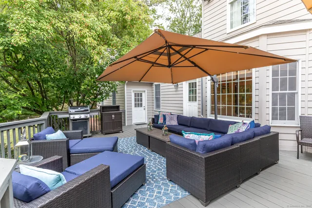 a view of a patio with couches table and chairs under an umbrella